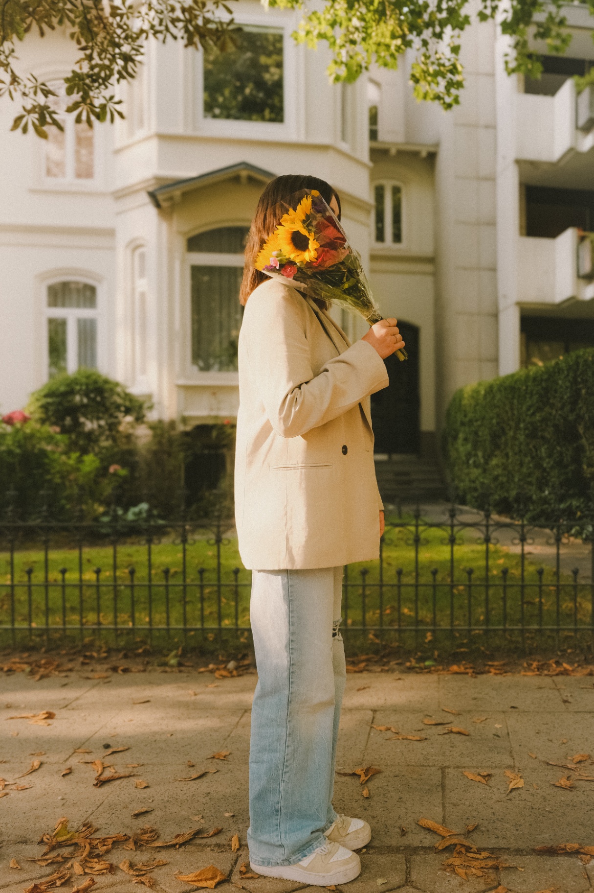 Frau mit Sonnenblumen vor Altbau